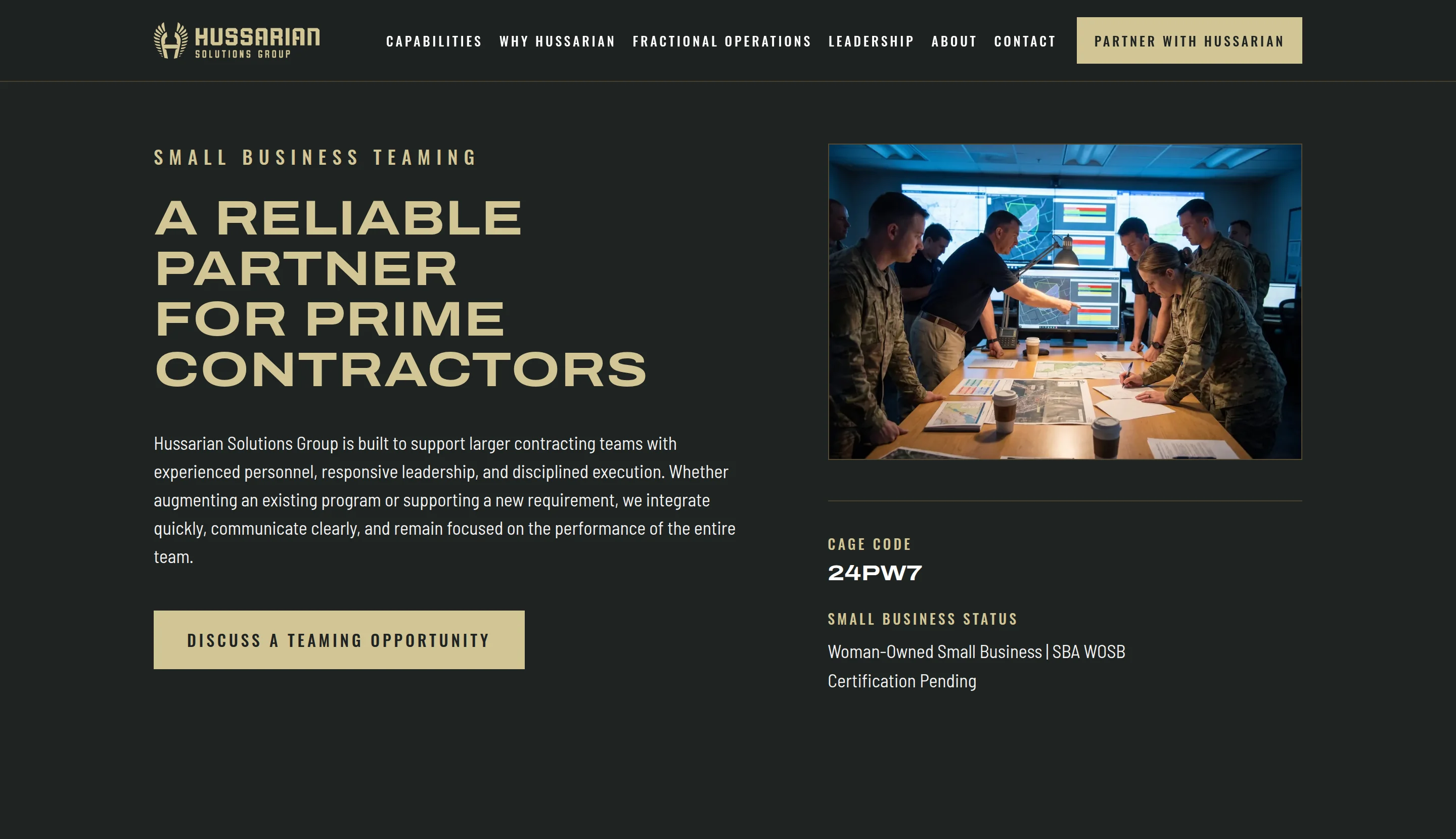 The Small Business Teaming section: the heading 'A Reliable Partner for Prime Contractors', a paragraph, a 'Discuss a Teaming Opportunity' button, and beside them a photograph of personnel around a table of maps with the CAGE code and small-business status listed beneath.